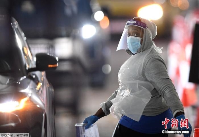 當(dāng)?shù)貢r間12月18日，英國政府公布的數(shù)據(jù)顯示，當(dāng)天英國新增奧密克戎毒株感染病例10059例。鑒于奧密克戎毒株感染病例激增，住院人數(shù)不斷上升，倫敦市長宣布倫敦進(jìn)入“重大事故”狀態(tài)。圖為倫敦的一個免下車檢測中心，一名醫(yī)務(wù)工作者正準(zhǔn)備對司機(jī)進(jìn)行核酸檢測。