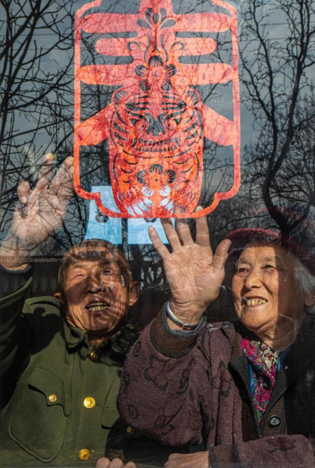 臘月里，霍州市師莊鄉(xiāng)馮南垣村村民師榮光(左)在災后重建的新家里貼窗花。(霍州市委宣傳部供圖)