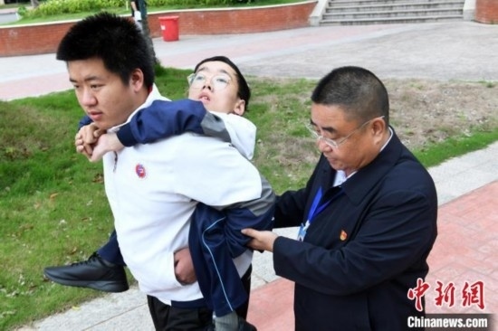 朱金祥背著鐘華強去教室上課的路上，也經(jīng)常碰到值班的校領(lǐng)導(dǎo)和老師前來搭把手。 卓忠偉 攝