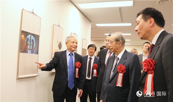 “湖州印象”攝影展主創(chuàng)、世界華人攝影協(xié)會(huì)副會(huì)長(zhǎng)馮學(xué)敏向吳江浩大使、福田康夫前首相等嘉賓介紹展出作品。（人民網(wǎng) 許可攝）