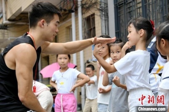 圖為大學生志愿者在組織孩子們參加體育健身活動。廖光福 攝