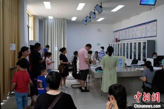 圖為在戶籍辦證廳內(nèi)排隊等待的家長和孩子。劉俊聰 攝