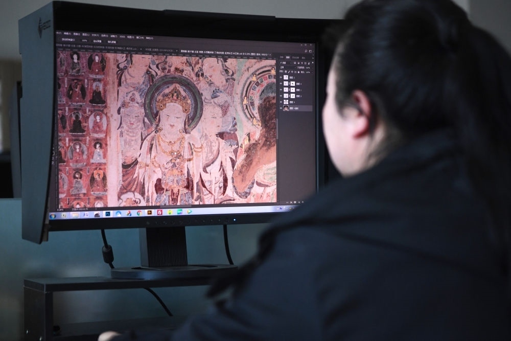 敦煌研究院文物數(shù)字化保護(hù)團(tuán)隊圖像處理人員年海麗在拼接壁畫圖像（2023年4月25日攝）。數(shù)字化探索為莫高窟的保護(hù)與傳承開辟了全新路徑，數(shù)字技術(shù)讓敦煌文物走出洞窟，跨出國門，走向“永久保存、永續(xù)利用”。新華社記者 陳斌 攝