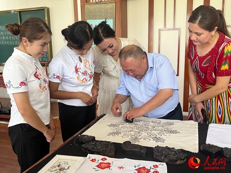 國(guó)家級(jí)非物質(zhì)文化遺產(chǎn)模戳印花布技藝傳承人吾吉阿西木?吾舒爾展示模戳印花布的制作過(guò)程。人民網(wǎng)記者 常雪梅攝