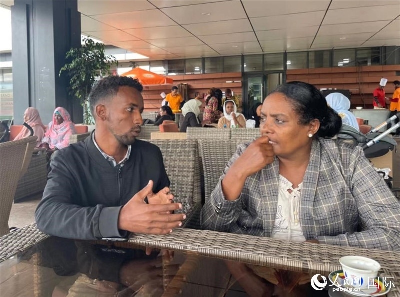 約漢斯（圖左）與德貝拉在友誼廣場(chǎng)咖啡廳交談。人民網(wǎng)記者 趙艷紅攝