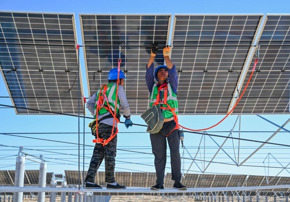 2023年7月22日，工人在位于內(nèi)蒙古杭錦旗庫布其沙漠億利生態(tài)示范區(qū)的蒙西基地庫布其200萬千瓦光伏治沙項(xiàng)目工地安裝光伏板。新華社記者 劉磊 攝
