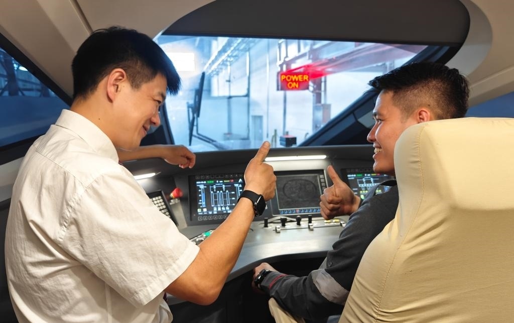 8月25日，在印度尼西亞萬隆的雅萬高鐵德卡魯爾動車所內(nèi)，中國師傅穆振（左）在向印尼火車司機(jī)塞蒂亞萬講解動車組出庫前的上電作業(yè)。