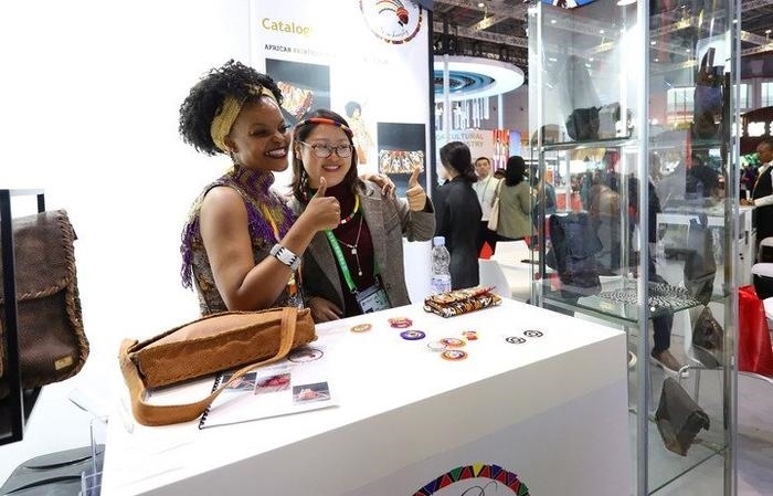 11月6日，一位參觀者（右）在第六屆進博會國家展南非展臺試戴傳統(tǒng)首飾。