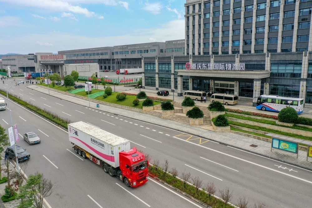 2023年10月11日，滿載筆記本電腦配件、發(fā)電機組件等產(chǎn)品的西部陸海新通道跨境公路班車從重慶南彭公路保稅物流中心駛出，將途經(jīng)廣西憑祥，直達(dá)越南（無人機照片）。新華社記者 黃偉 攝