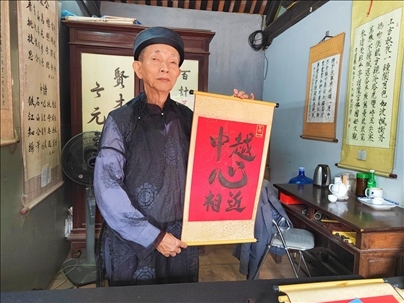 越南首都河內(nèi)文廟內(nèi)，阮明珠展示“中越心相近”書(shū)法作品。