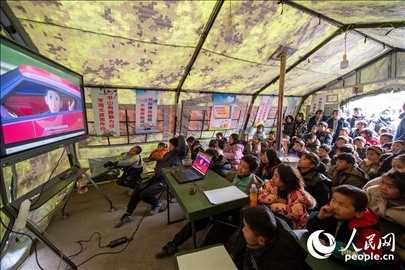 12月22日，在積石山縣大河家鎮(zhèn)大河村安置點(diǎn)，陸軍76集團(tuán)軍某旅搭建的“臨時(shí)學(xué)?！眱?nèi)，小朋友正在看動(dòng)畫(huà)片。人民網(wǎng)記者 翁奇羽攝