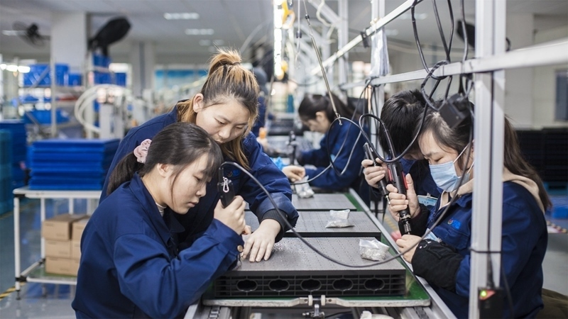 在新亞勝光電的產(chǎn)品線上，工人正進行產(chǎn)品組建和安裝布線。受訪者供圖