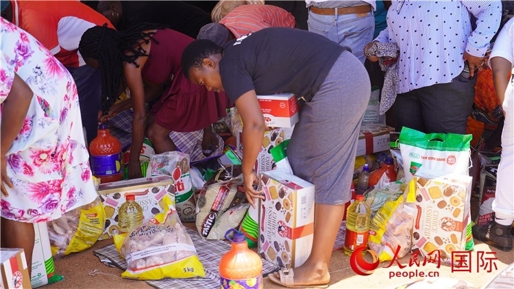 當?shù)厣鐓^(qū)家庭領取物資。人民網 張茜攝