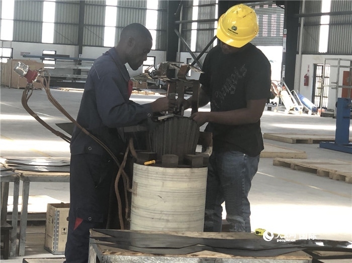 經(jīng)貿(mào)合作區(qū)廠房?jī)?nèi)，當(dāng)?shù)毓と苏诰o張作業(yè)。人民網(wǎng)記者 黃培昭攝