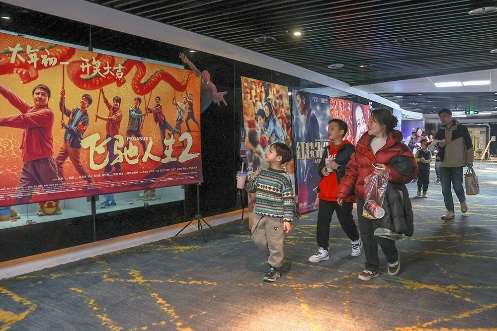 △ 2024年2月16日，在江西贛州一家電影院，觀眾從春節(jié)檔電影的宣傳展板前走過(guò)。