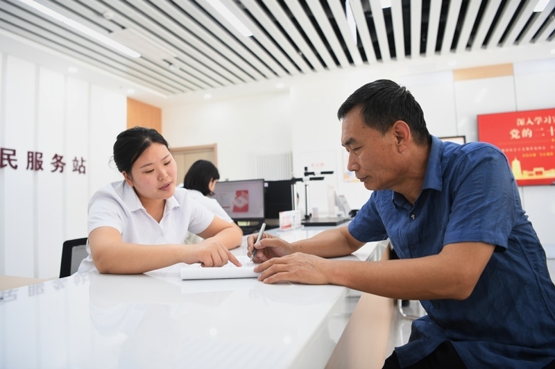 2023年5月23日，河北雄安新區(qū)容東片區(qū)南文營社區(qū)居民（右）在社區(qū)便民服務(wù)站辦理業(yè)務(wù)。