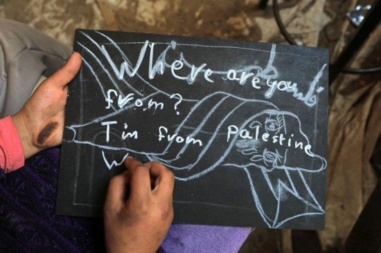 2023年12月28日，一名學(xué)生在加沙地帶南部城市拉法一所學(xué)校的臨時(shí)教室中寫下“我來自巴勒斯坦”的字樣。新華社發(fā)（里澤克·阿卜杜勒賈瓦德攝）