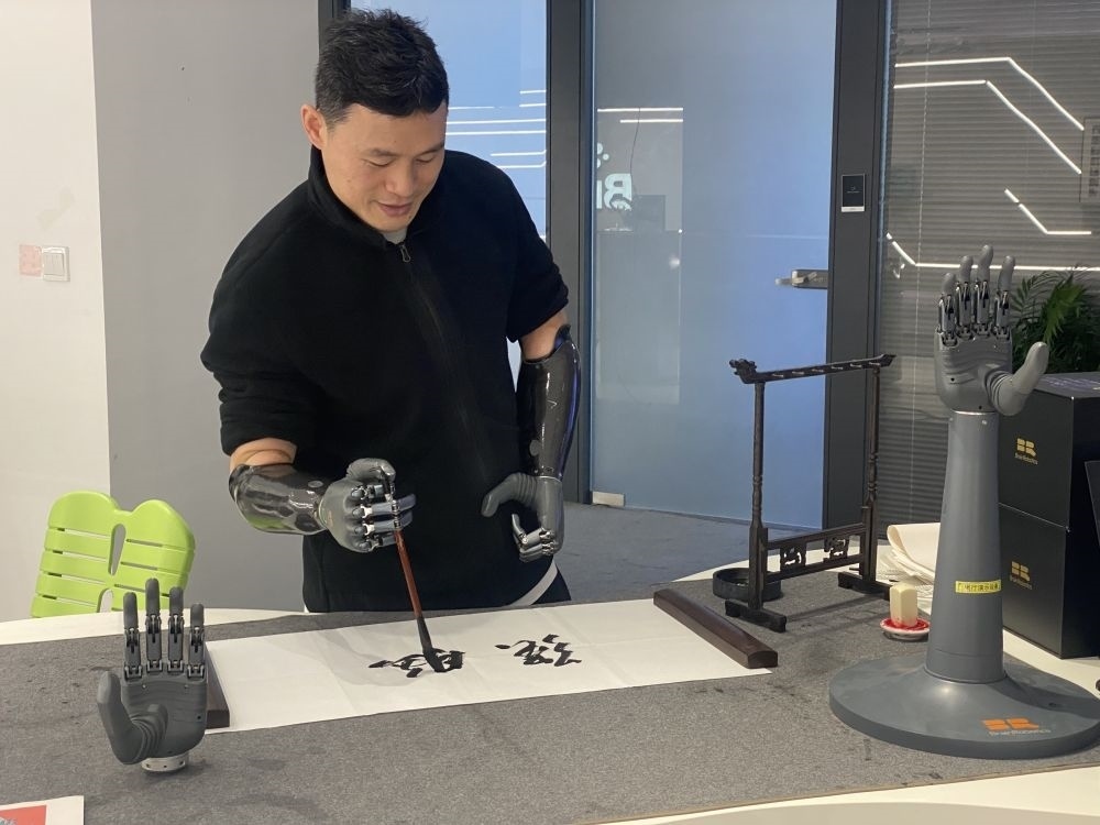 2024年3月29日，在浙江強腦科技有限公司展廳內，失去雙手的產(chǎn)品體驗官倪敏成依靠智能仿生手寫毛筆字。新華社記者 魏一駿 攝
