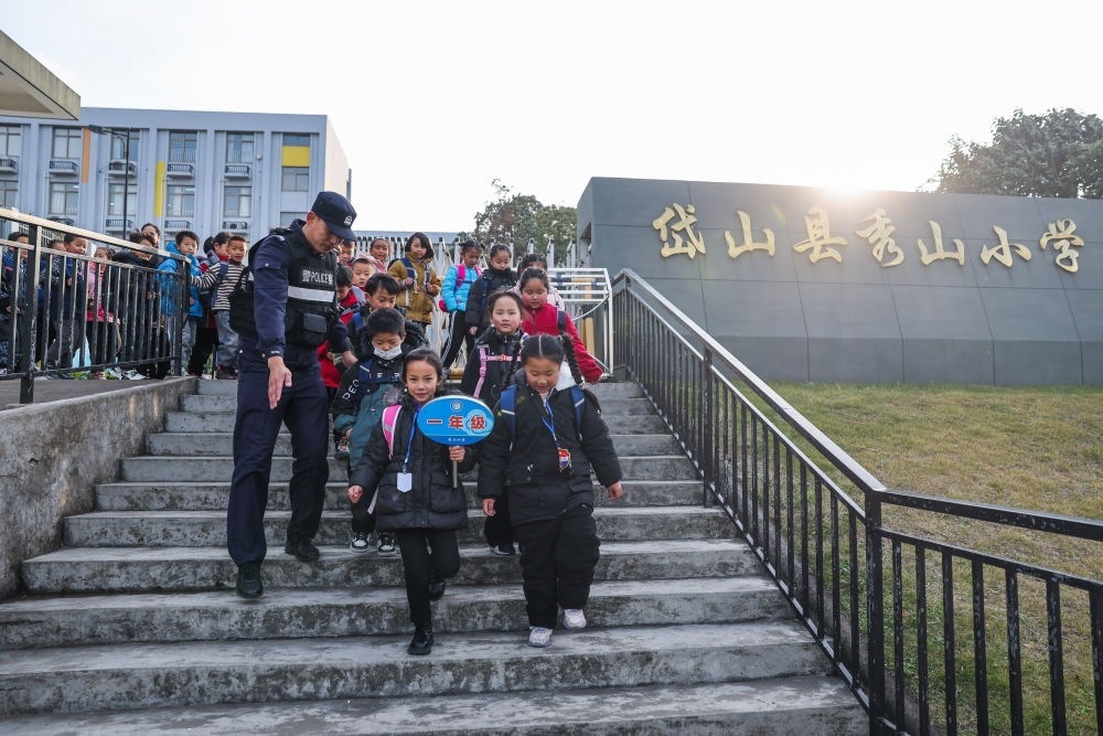 2023年12月20日，秀山派出所民警在秀山小學放學時間參與“護學崗”維持秩序，同時接獨自放學的學生去“民生小鋪”。浙江省舟山市岱山縣公安局秀山派出所聯(lián)合鄉(xiāng)鎮(zhèn)、社區(qū)成立“民生小鋪”，為當?shù)鼐用?、外來務工人員及其子女等服務，協(xié)助解決外來務工人員在工作、生活等方面的矛盾和問題，助力鄉(xiāng)鎮(zhèn)基層治理。新華社記者 徐昱 攝