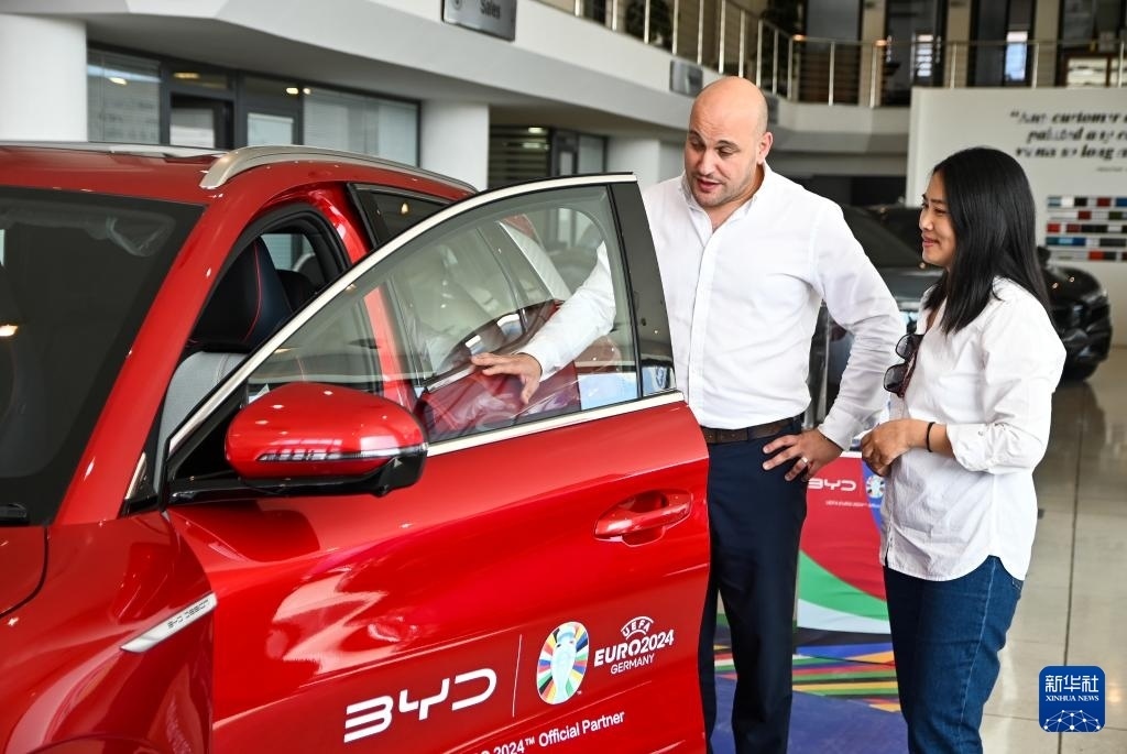 2024年5月29日，在馬耳他比爾基卡拉，馬耳他哈桑-扎米特汽車公司首席執(zhí)行官德古阿拉（左）介紹一輛比亞迪純電動汽車。新華社發(fā)（喬納森·博格 攝）
