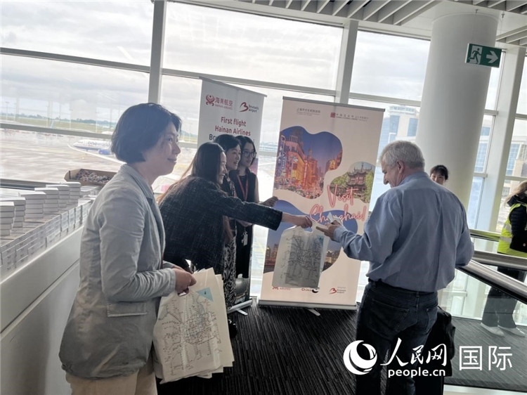 圖為工作人員向乘客發(fā)放復(fù)航首班禮物。 牛瑞飛攝