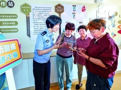 浙江湖州民警指導(dǎo)居民加入湖州“e企安”微信群，實時接收反詐信息。新華社發(fā)