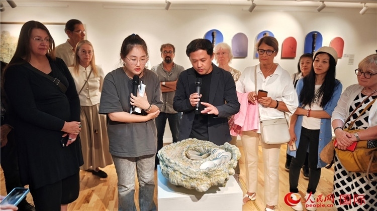 參展人、景德鎮(zhèn)陶瓷大學(xué)設(shè)計(jì)藝術(shù)學(xué)院副院長余劍峰（中）向來賓介紹參展作品。人民網(wǎng)記者 殷淼攝