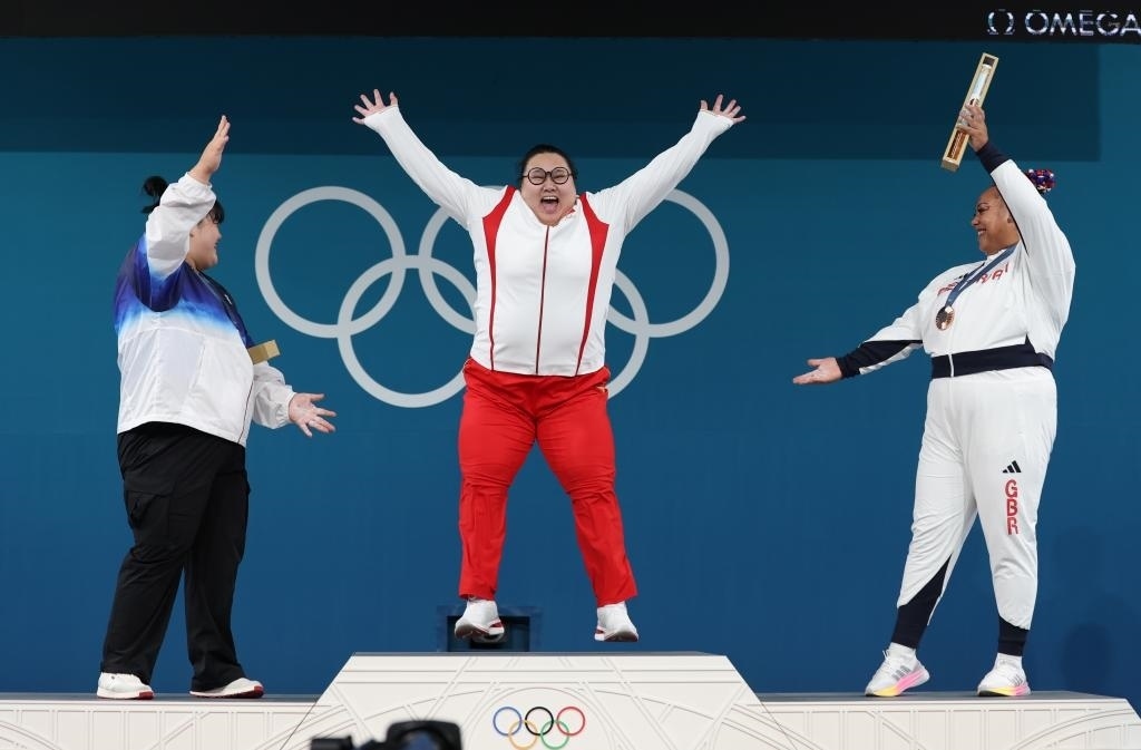 中國(guó)選手李雯雯（中）在巴黎奧運(yùn)會(huì)舉重女子81公斤以上級(jí)頒獎(jiǎng)儀式中登上領(lǐng)獎(jiǎng)臺(tái)（2024年8月11日攝）。新華社記者 楊磊 攝