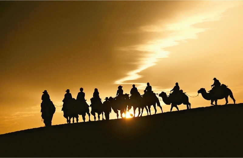 新時代以來，文化和旅游深度融合發(fā)展體制機制不斷健全，成功走出了一條獨具特色的中國旅游發(fā)展之路。圖為2024年9月1日清晨，游客在甘肅省敦煌市鳴沙山月牙泉景區(qū)乘騎駱駝，欣賞大漠風光，體驗絲路風情。 新華社發(fā) 張曉亮/攝