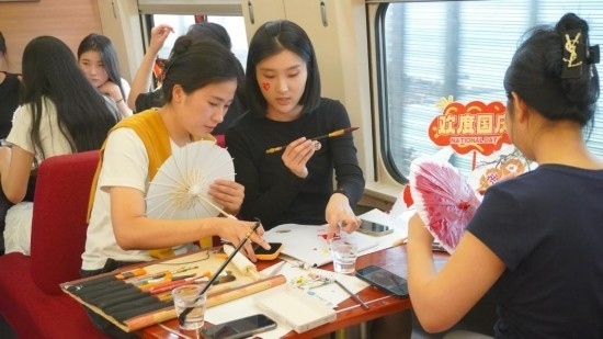 10月1日，旅客們在G1634次列車上給油紙傘作畫。新華社記者周義 攝