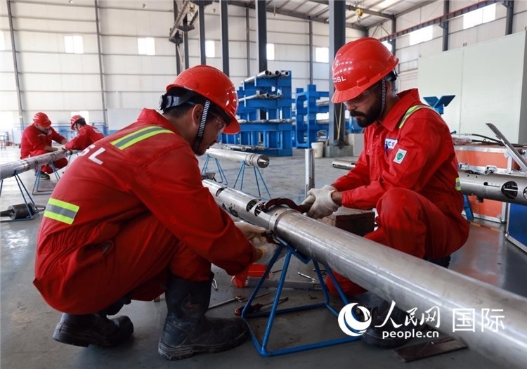 中伊員工共同在檢修鉆井設(shè)備。人民網(wǎng)記者管克江攝