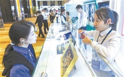 在北京麗澤商務(wù)區(qū)，工作人員（右一）介紹數(shù)字人民幣SIM卡硬錢(qián)包。新京報(bào)記者 陶冉攝