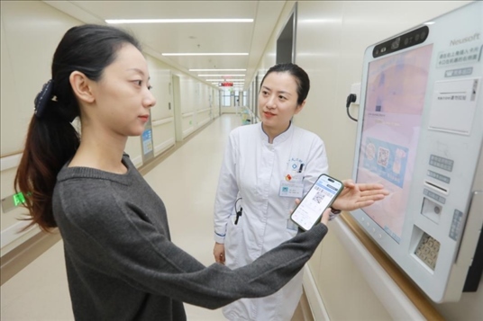 醫(yī)護人員引導患者在自助機前辦理自助入院手續(xù)。圖片來源：山東第一醫(yī)科大學第二附屬醫(yī)院