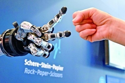 在德國漢諾威工博會上，參觀者與一款智能機器人進(jìn)行“石頭剪子布”游戲。新華社發(fā)