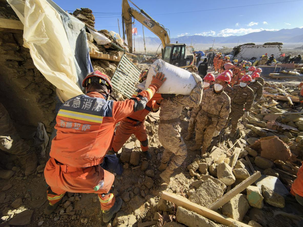 1月11日，定日縣長所鄉(xiāng)古榮村，應(yīng)急消防等救援人員排隊(duì)接力搶運(yùn)掩埋在倒塌房屋下的群眾財(cái)物。人民日報(bào)記者楊翹楚攝