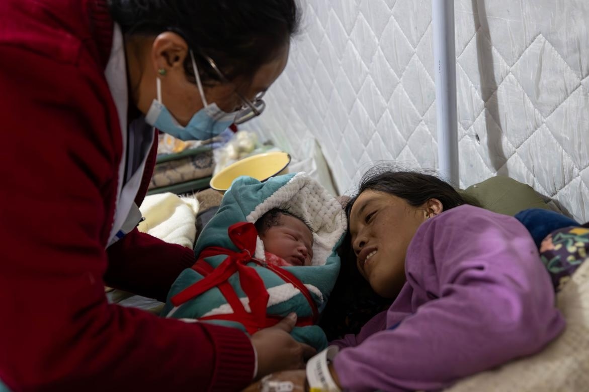 1月10日，定日縣中心醫(yī)院的婦產(chǎn)科醫(yī)生悉心照看一位母親和她懷里的新生兒。人民日報(bào)記者張武軍攝