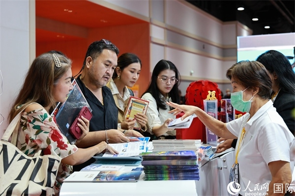 外國(guó)觀眾在中國(guó)展臺(tái)仔細(xì)閱讀赴華旅游介紹，向工作人員咨詢關(guān)于中國(guó)美食和景點(diǎn)的詳細(xì)信息。人民網(wǎng)記者 白元琪攝