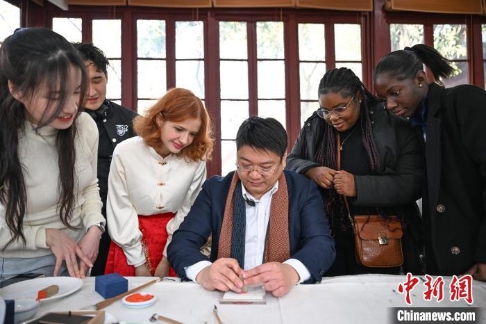 1月20日，篆刻家王臻向外籍留學生展示篆刻印章。當日，來自巴西、馬來西亞、加納、哈薩克斯坦的外籍留學生在浙江杭州西泠印社體驗福貼、春聯(lián)和篆刻，感受古老的中國傳統(tǒng)文化。中新社記者 王剛 攝