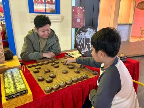 柯秋楓與市民下椰雕象棋。人民網(wǎng) 陳葉欣攝