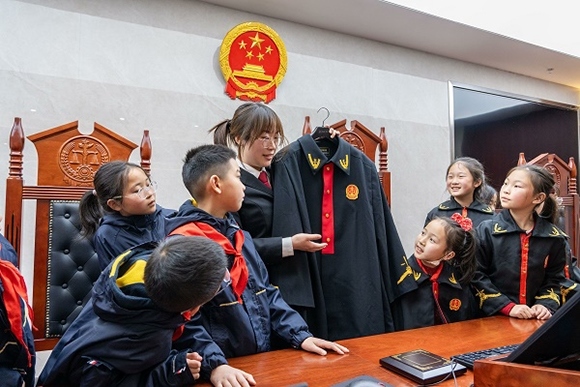 圖②：干警向同學(xué)們介紹法袍。