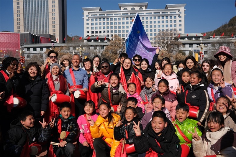 中外青年學(xué)子在安塞文化廣場(chǎng)觀看陜北腰鼓和大秧歌表演后合影留念，大家踏著鼓點(diǎn)共舞，翻飛的紅綢與躍動(dòng)的身影交織，在黃土地廣場(chǎng)上繪出一幅生動(dòng)的陜北民俗互動(dòng)畫卷