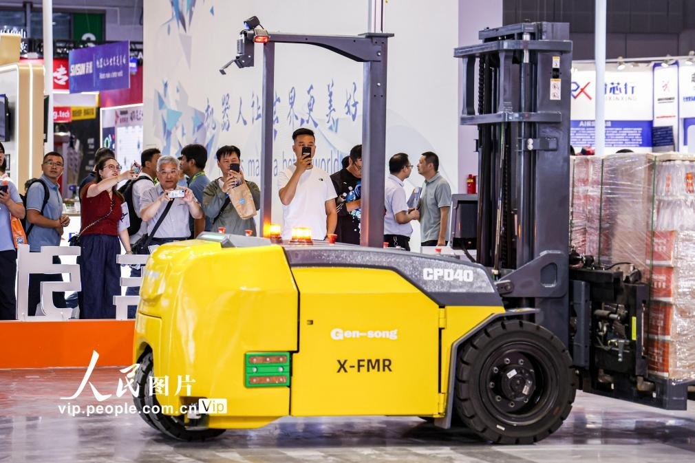 第24屆中國工博會現(xiàn)場，觀眾觀看叉取機(jī)器人作業(yè)演示。王初攝（人民圖片網(wǎng)）