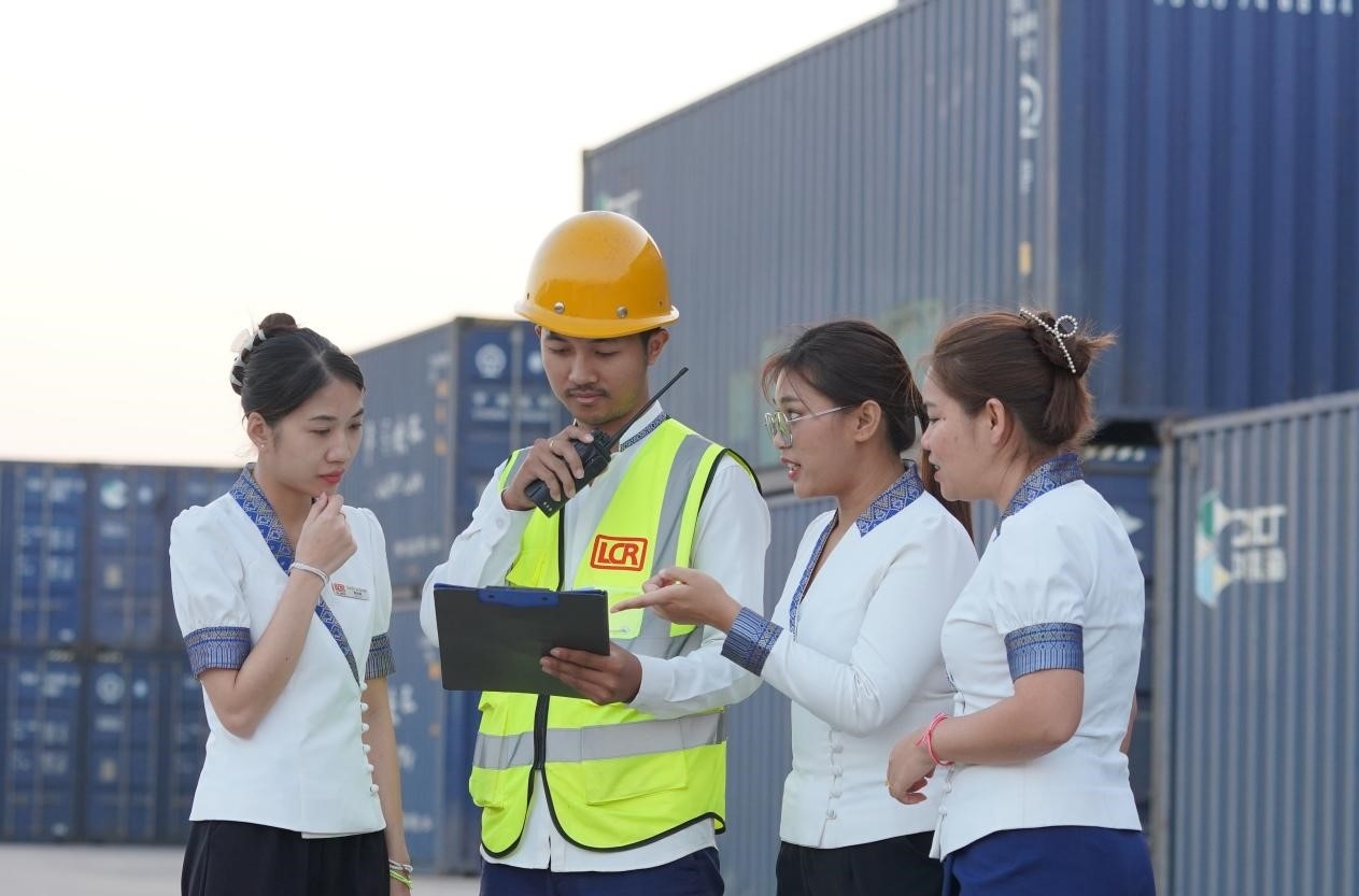 萬象南站貨運值班員陳尼啦（左一）與同事在一起討論工作。老中鐵路有限公司供圖