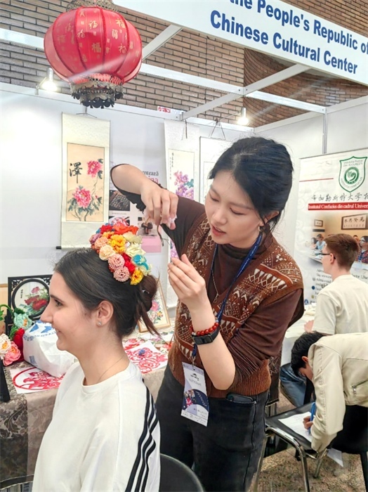 展覽正值羅馬尼亞迎春花節(jié)，國際中文教師志愿者潘婧穎向游客們介紹了國家非物質(zhì)文化遺產(chǎn)——福建泉州的簪花文化。布加勒斯特大學孔子學院供圖。