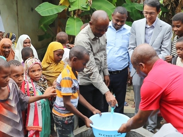 在日前舉行的安全供水工程揭牌儀式上，當?shù)匦∨笥言诠┧c接水。 施亮攝