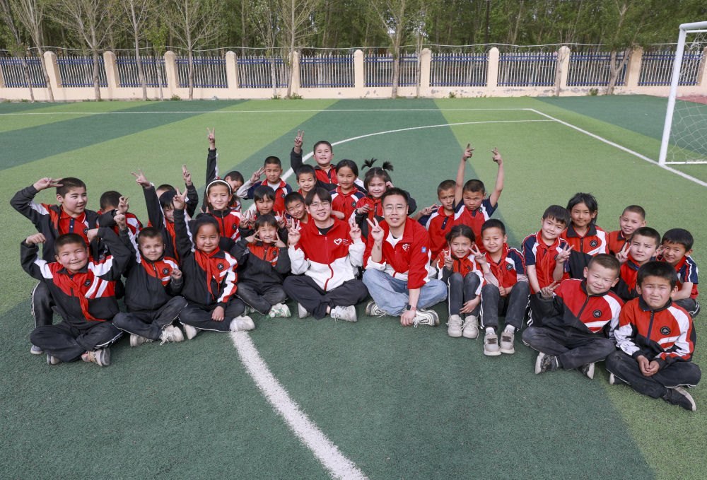 4月23日，在新疆克州阿圖什市哈拉峻鄉(xiāng)謝依特小學(xué)，支教教師王俊文（中左）、李軻凡（中右）和學(xué)生在一起。