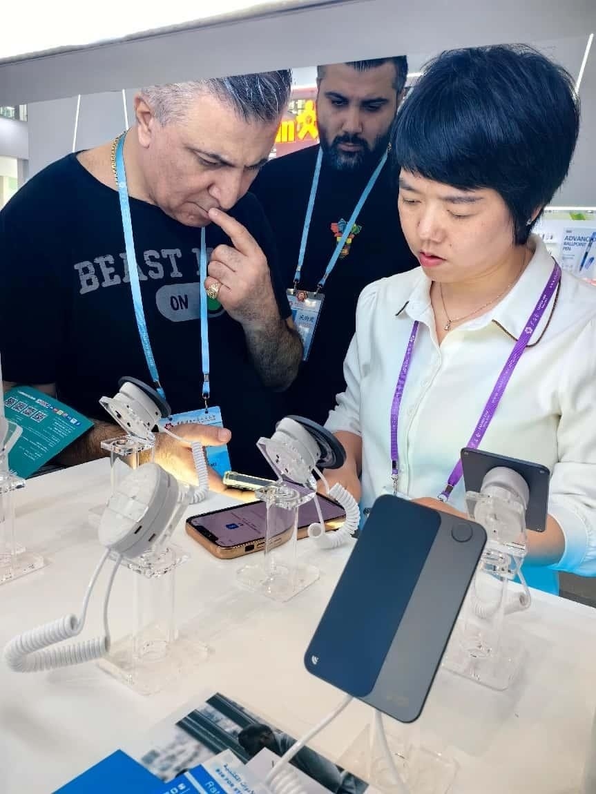 展臺(tái)工作人員向外商展示“AI TOP翻譯終端”。圖片來(lái)源：受訪者提供